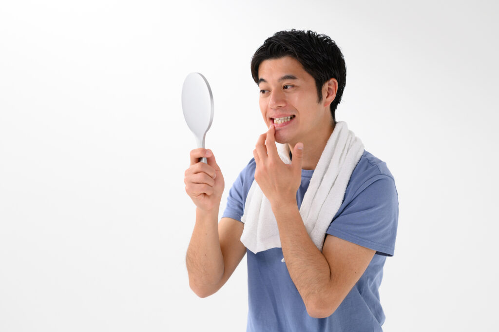 歯列矯正後に歯並びを確認する男性|男性の口元ケアや清潔感アップに効果的な矯正治療